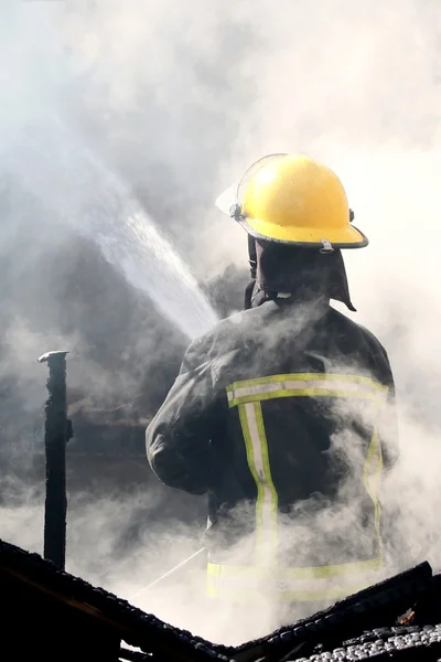 Feuerwehrmann löscht Hausbrand lizenzfreie Stockfotos