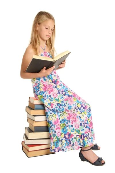 Söt skolflicka sitter på böcker — Stockfoto