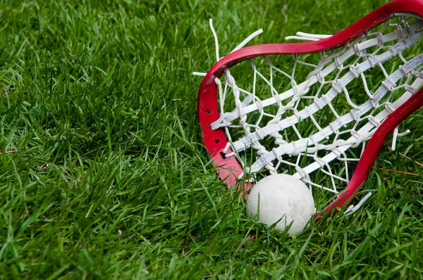 Meninas cabeça de lacrosse e bola cinza na grama — Fotografia de Stock