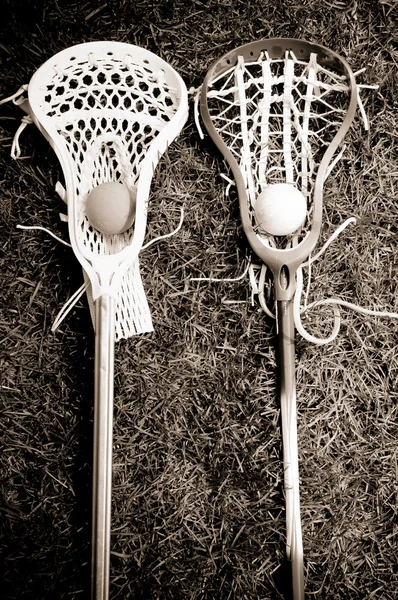 Two lacrosse heads and sticks with ball on grass - black and whi — Stock Photo, Image