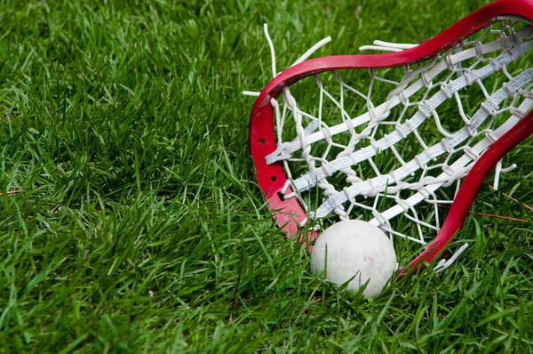Meisjes lacrosse hoofd en grijze bal op gras Stockfoto