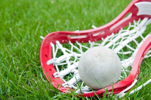 Meisjes lacrosse hoofd en grijze bal op gras Stockfoto