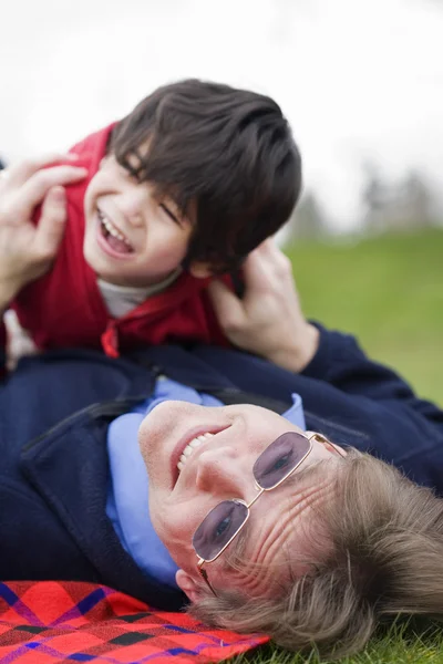 Отец играет с сыном-инвалидом на траве в парке — стоковое фото