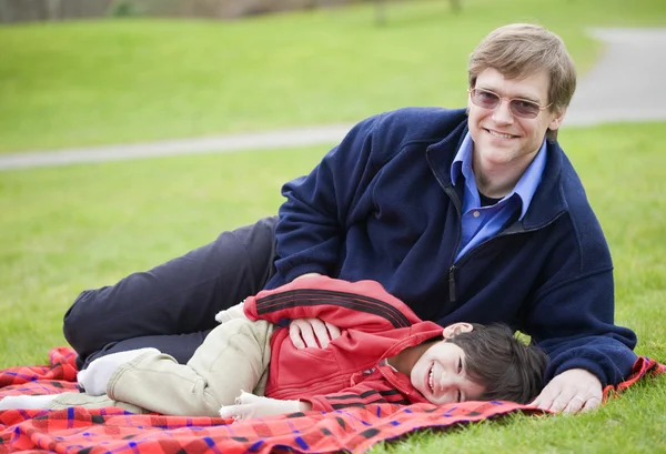 父亲躺在毯子上，儿子在公园 — 图库照片