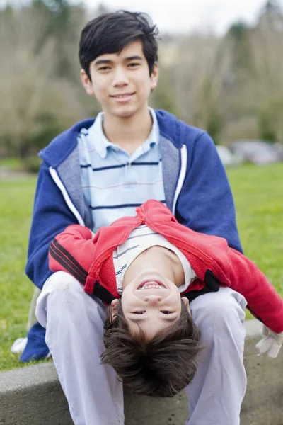 Big brother taking care of disabled little brother — Stock Photo, Image
