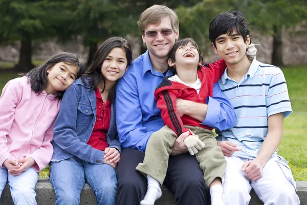 Feliz familia interracial disfrutando del día en el parque con hijo discapacitado — Foto de Stock