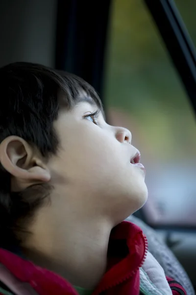Vier-jarige jongen kijkt rustig uit auto raam — Stockfoto