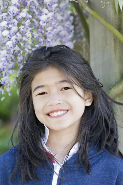 年轻美丽的女孩站在紫藤葡萄藤下 — 图库照片