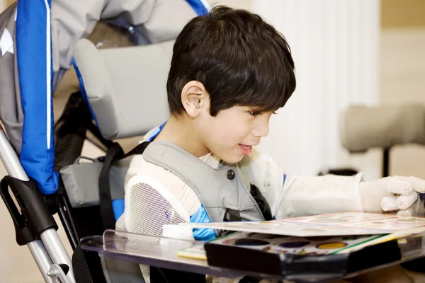 4-летний мальчик-инвалид, учится или читает в инвалидном кресле — стоковое фото