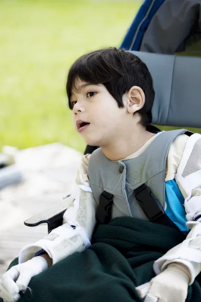 Четырехлетний мальчик-инвалид с церебральным параличом сидит на улице — стоковое фото
