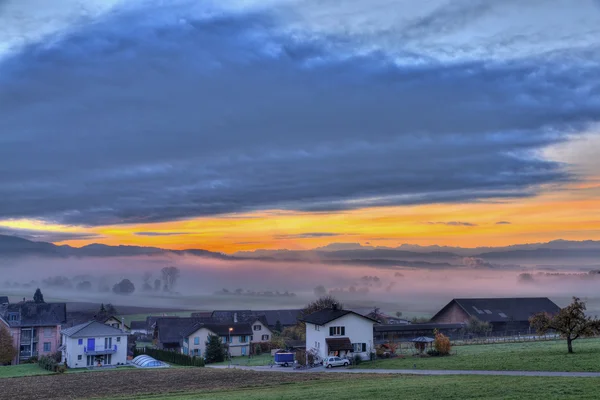 Ανατολή του ηλίου πάνω από το ορεινό χωριό με ομίχλη αεροπλάνα — Φωτογραφία Αρχείου