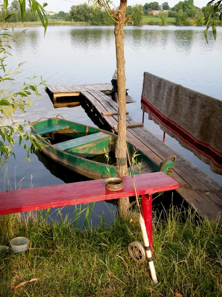 Bancă roșie din lemn cu o tijă de pescuit — Fotografie, imagine de stoc