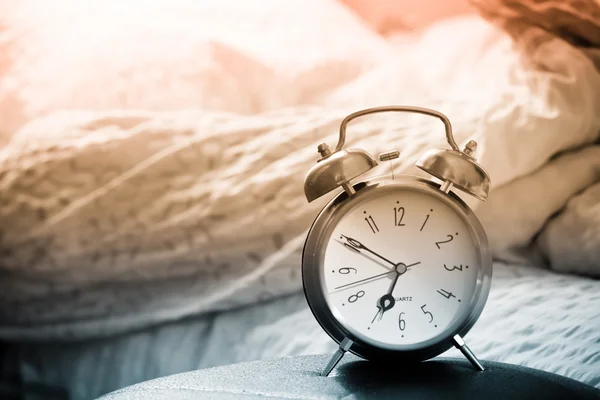 Hodiny a postel zobrazeno probuzení času v ložnici — Stock fotografie