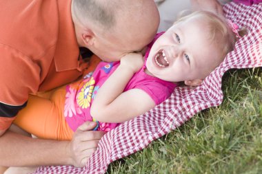 Loving Dad Tickles Daughter in Park clipart