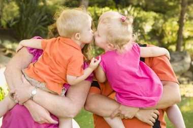 Mom and Dad Holding Kissing Brother and Sister Toddlers clipart