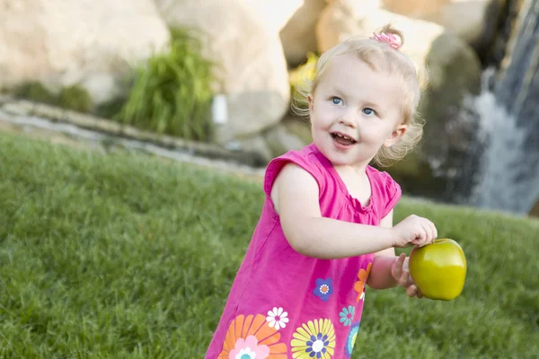 Usměvavá mladá dívka v parku drží jablko — Stock fotografie