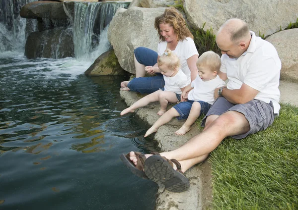 Молодая семья с близнецами наслаждается водой в парке — стоковое фото