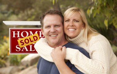 Happy Couple in Front of Sold Real Estate Sign clipart