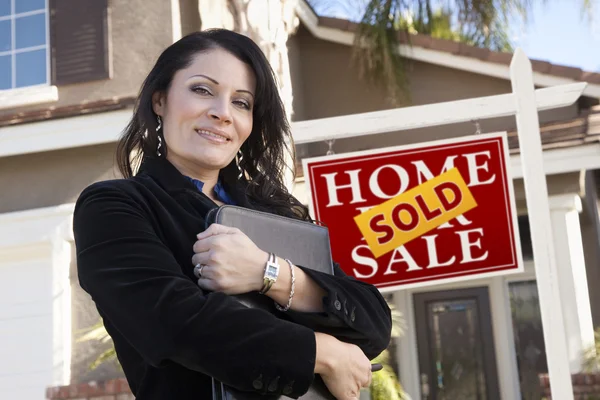 Hispanic Woman in Front of Real Estate Sign and New Home Stock Photo