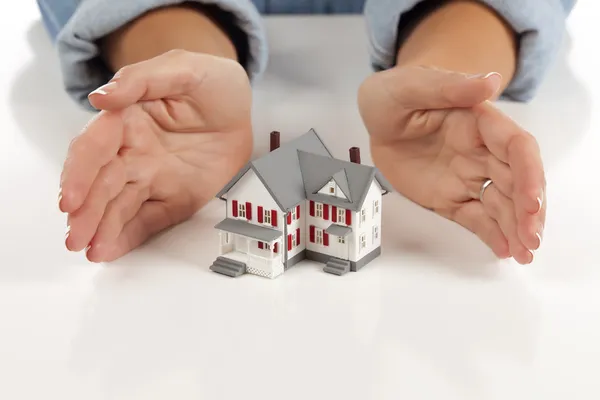Zenske ruce kolem modelu domu — Stock fotografie