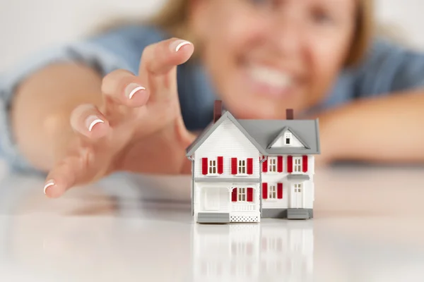 stock image Smiling Woman Reaching for Model House on White