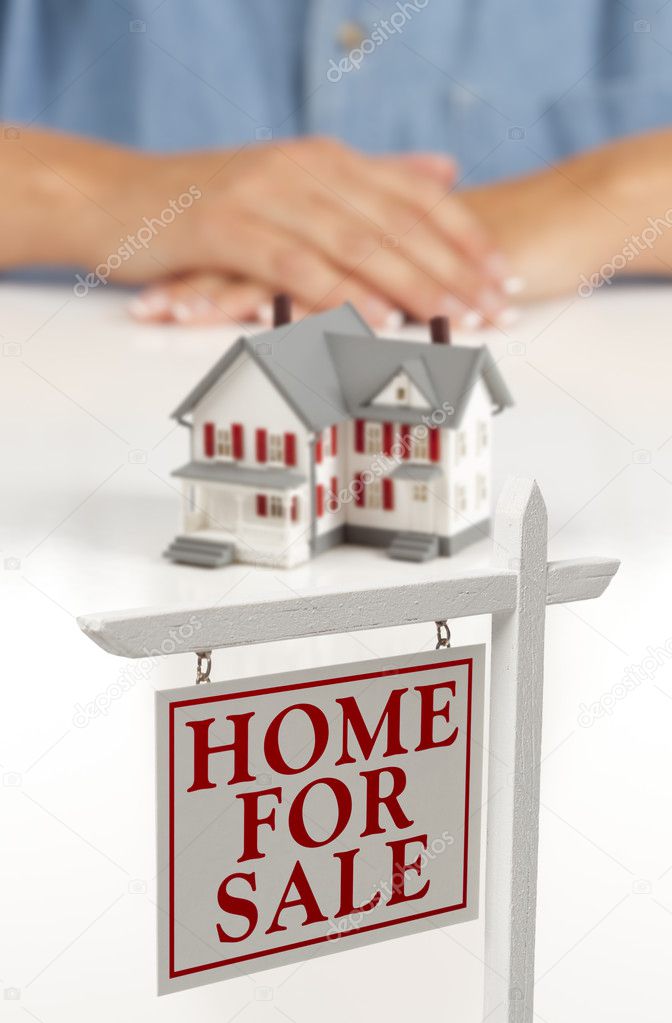 Womans Hands Behind House and Real Estate Sign in Front
