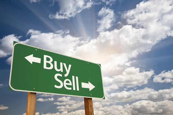 Comprar, vender sinal de estrada verde contra nuvens — Fotografia de Stock