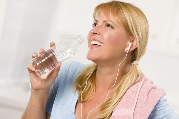 Hübsche blonde Frau mit Handtuch trinkt aus Wasserflasche — Stockfoto