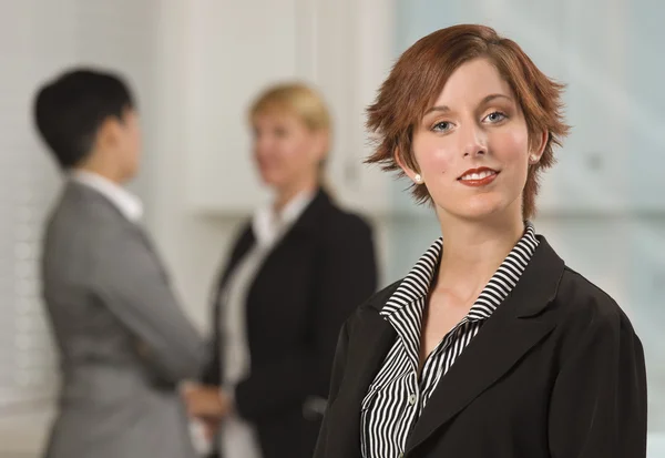 Vrij rood haired zakenvrouw met collega's achter — Stockfoto