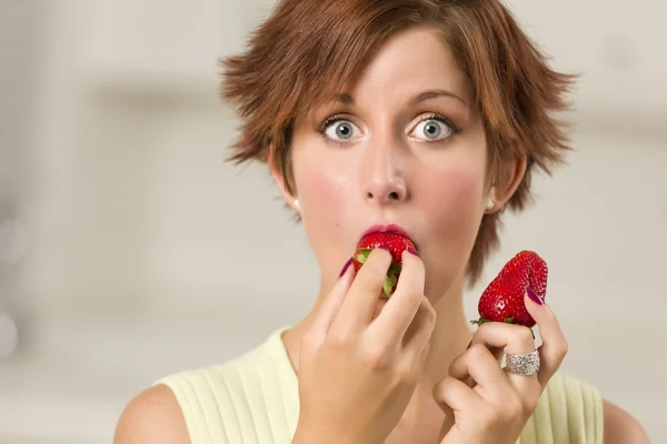 Довольно широкоглазый рыжеволосая женщина кусающая клубнику — стоковое фото