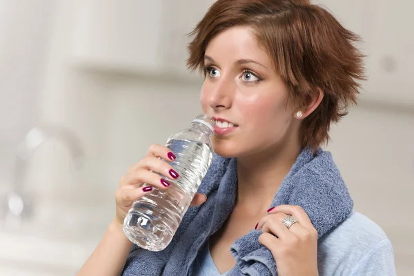 Hübsche rothaarige Frau mit Handtuch, die aus Wasserflasche trinkt — Stockfoto