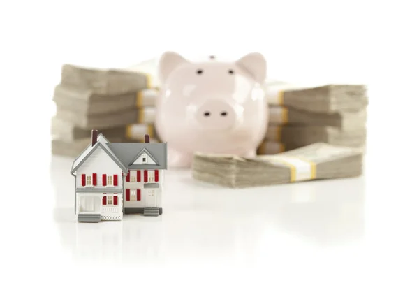 Mały dom i piggy bank z stosy pieniędzy — Zdjęcie stockowe