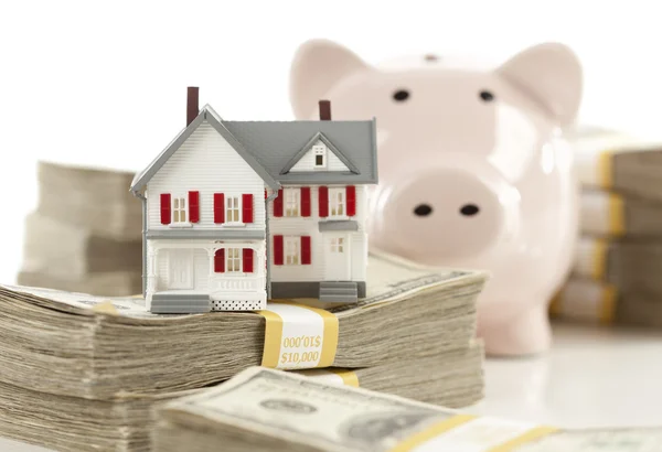 Mały dom i piggy bank z stosy pieniędzy — Zdjęcie stockowe