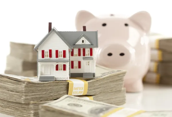 Klein huis en spaarvarken met stapels geld — Stockfoto