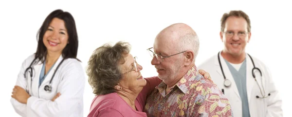 Seniorenpaar mit Ärzten oder Krankenschwestern im Hintergrund — Stockfoto