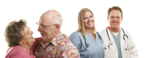 Äldre par med läkare eller sköterskor bakom — Stockfoto