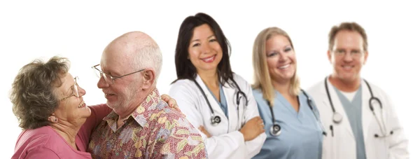 Seniorenpaar mit Ärzten oder Krankenschwestern im Hintergrund — Stockfoto