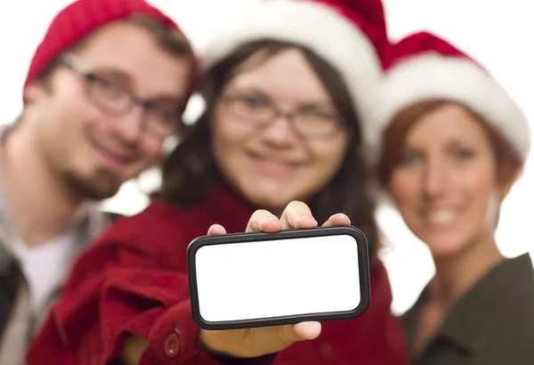 Menina com amigos e chapéus de Santa segurando telefone inteligente em branco — Fotografia de Stock
