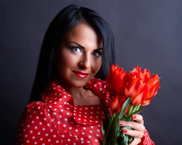 Νεαρή γυναίκα με κόκκινα λουλούδια — Φωτογραφία Αρχείου