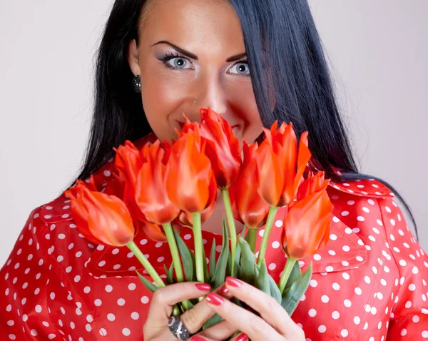Νεαρή γυναίκα με κόκκινα λουλούδια — Φωτογραφία Αρχείου
