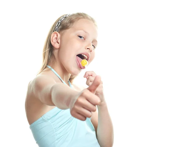 Cheerful little girl with lollipop showing thumbs up — Stock Photo, Image