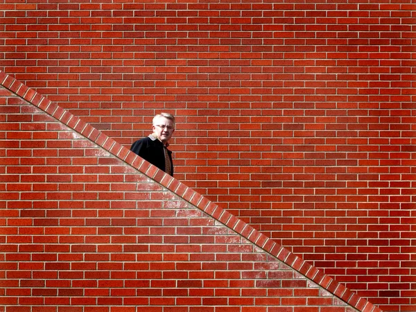 Mannen trap bakstenen muur lopen — Stockfoto