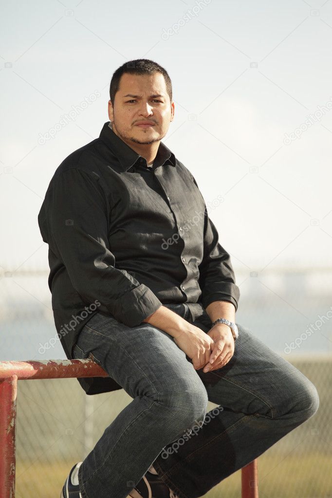 Latino man sitting outdoors