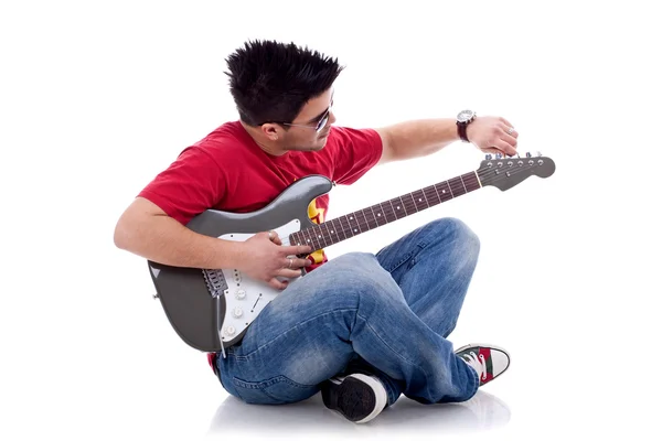 Guitarrista sentado calibrando su guitarra eléctrica — Foto de Stock