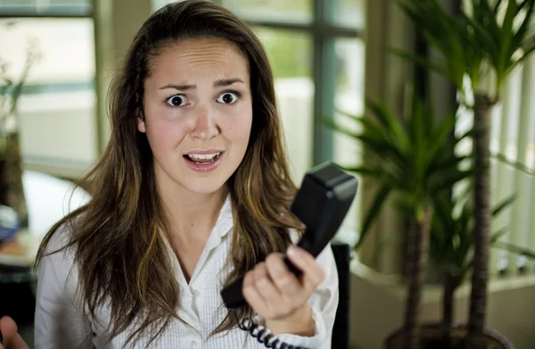 Frau sitzt gestresst hinter Schreibtisch — Stockfoto