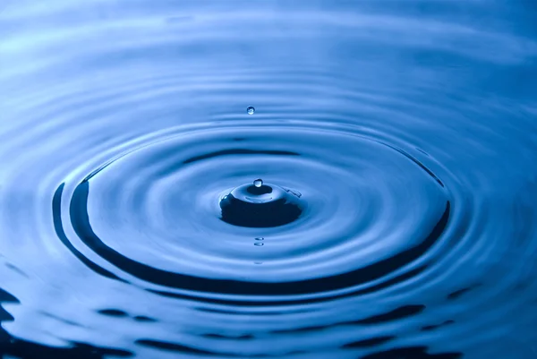 Water droplet tegen blauwe achtergrond — Stockfoto