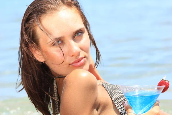 Молодая женщина на пляже с коктейлем — стоковое фото