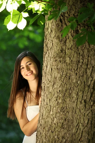 Szczęśliwa młoda kobieta za drzewa — Zdjęcie stockowe