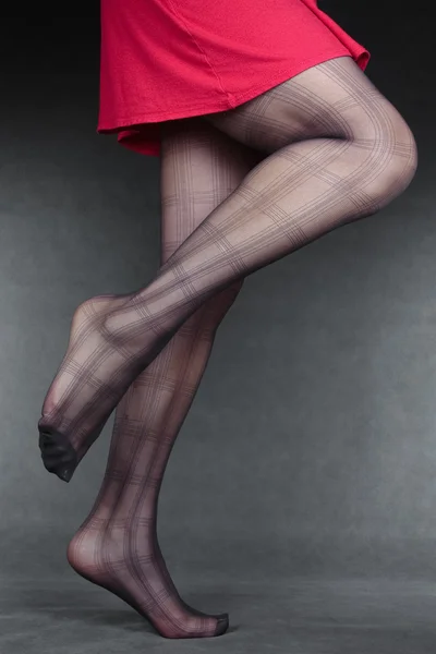 Vacker kvinna benen bär strumpbyxor & röd klänning över grå — Stockfoto