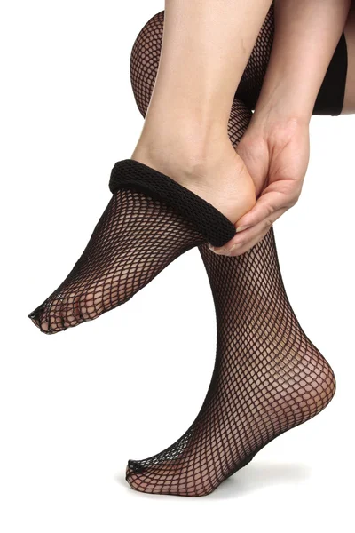 Woman feet puting on black tights — Stock Photo, Image